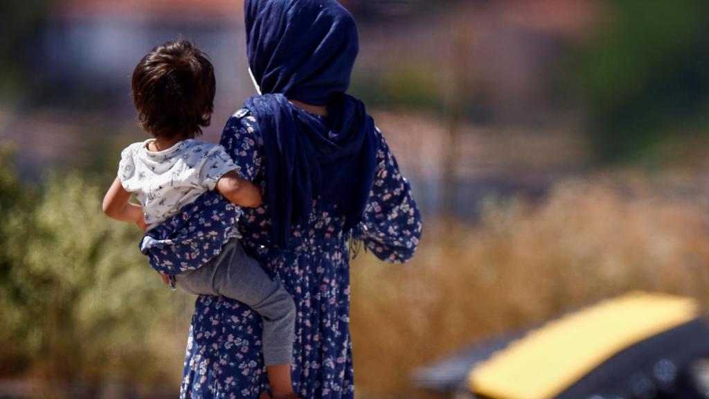 Una mujer con su hijo en brazos en el campamento de la Cruz Roja en Avezzano (Italia).