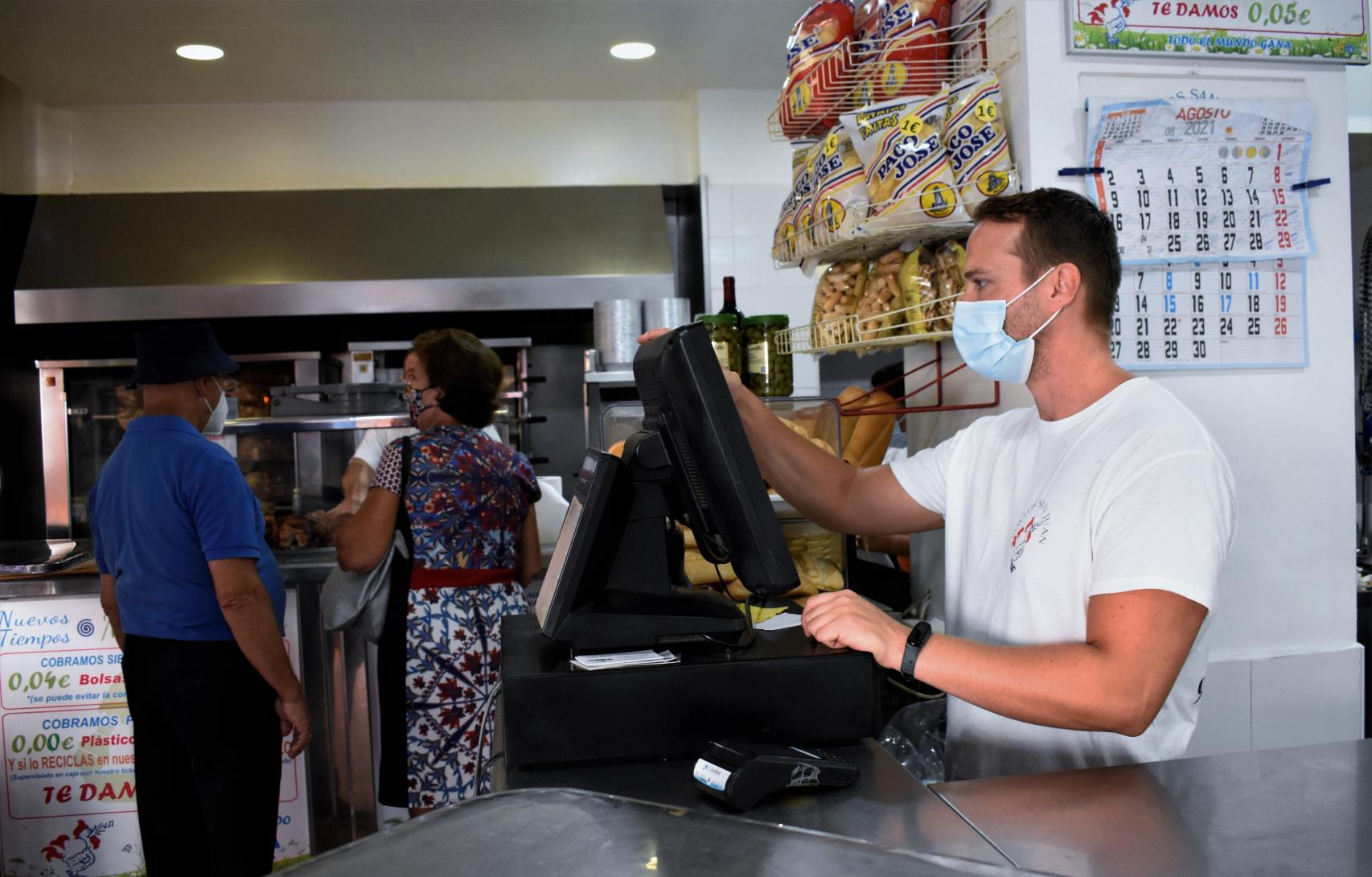 Unos clientes madrigan para llevarse uno de los pollos.
