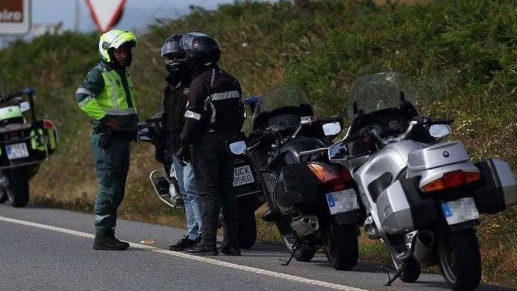 Un agente de la Guardia Civil dialoga con dos motoristas en la carretera.