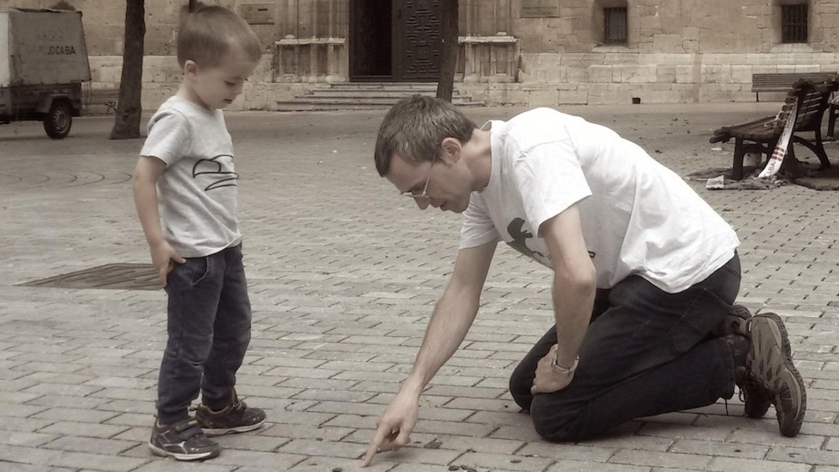 Ruben Santos apunta a un fósil en el pavimento de una ciudad.