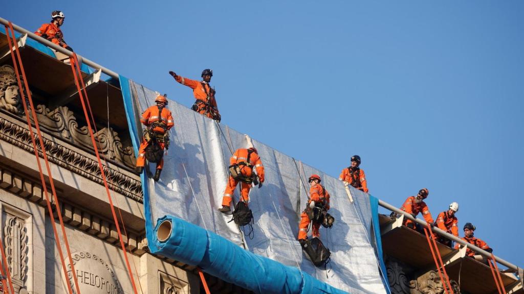 Operarios descolgando las telas sobre el monumento.