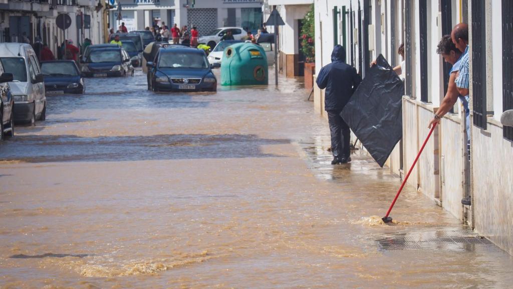 Vecinos de Lepe (Huelva) observando el nivel de agua en una calle inundada.