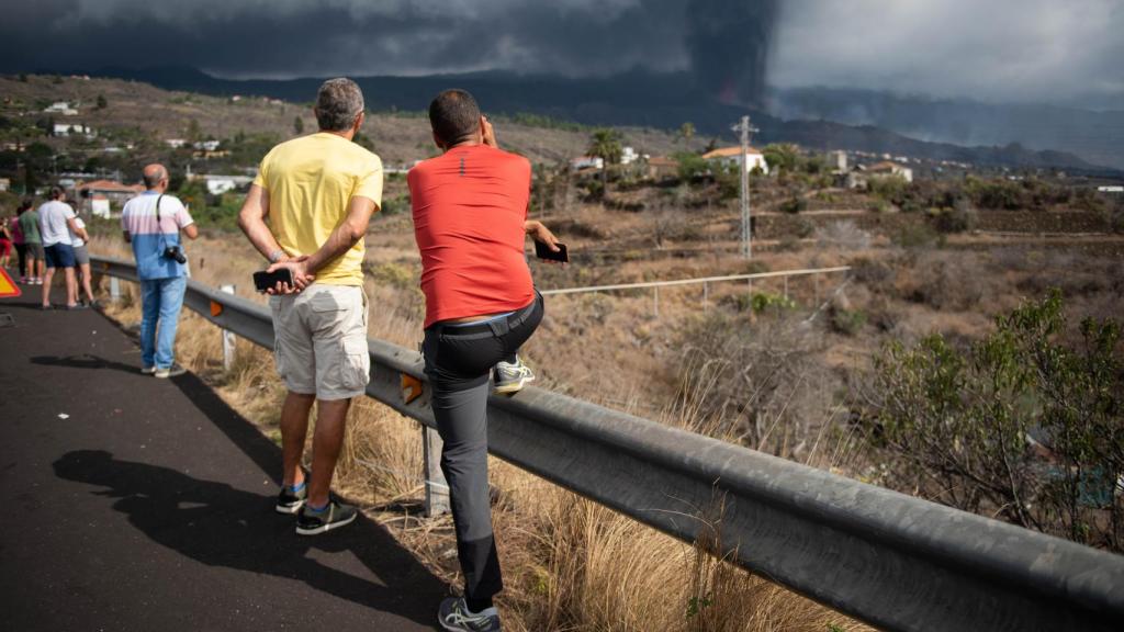 Algunos curiosos se agolpan en el arcén para ver el volcán este sábado.