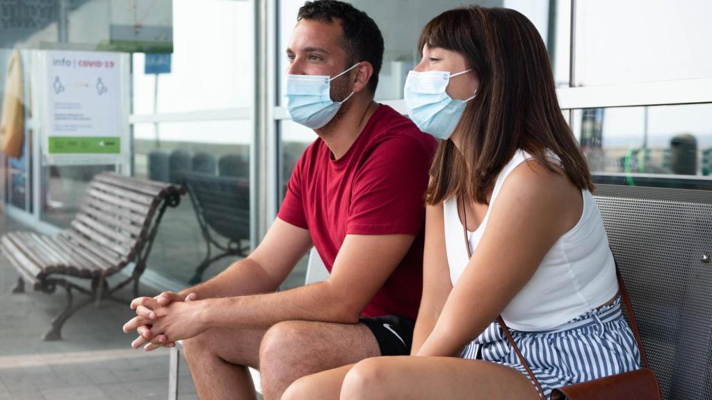 Noelia y Andrés esperan el autobús para ir al hotel desde el aeropuerto.