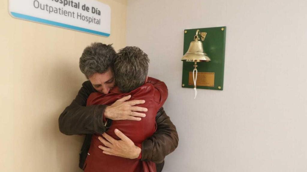 La pareja abrazándose tras tocar la campana de los sueños juntos.