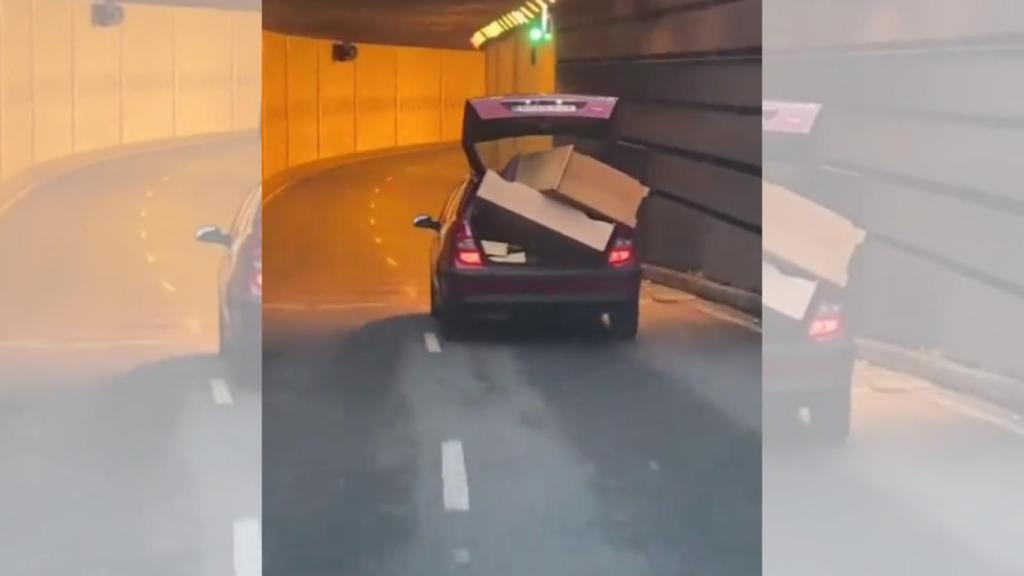 Un coche cargado y con el maletero abierto, en circulación por el centro de Vigo