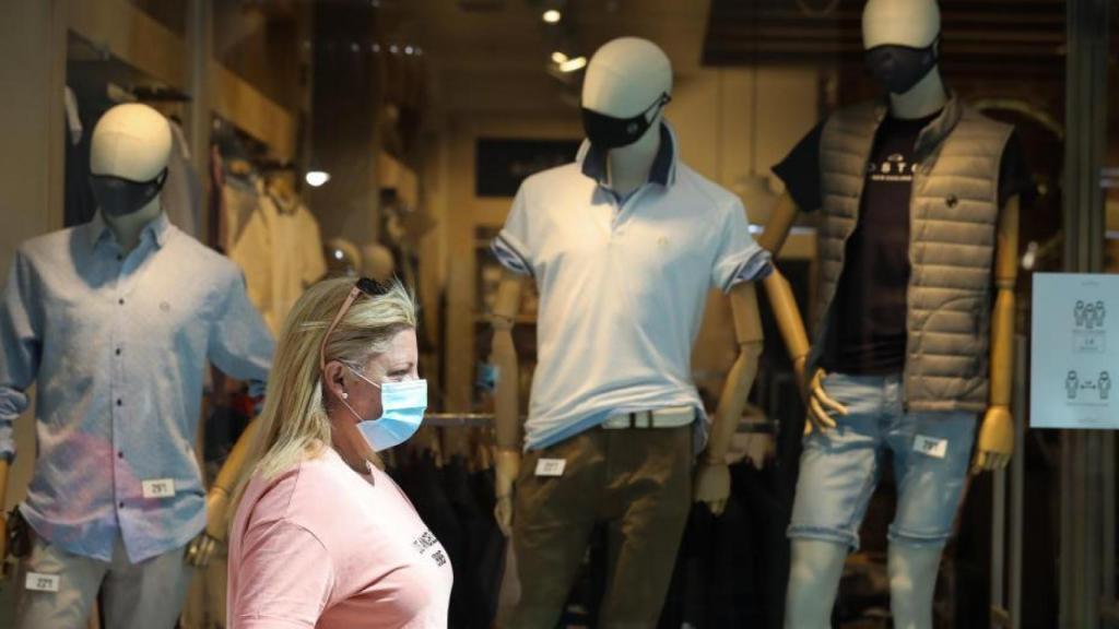 Un mujer pasa delante de una tienda de ropa.