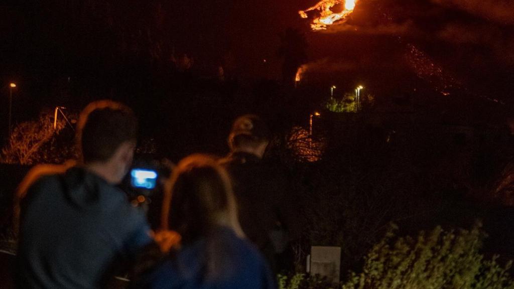 Dos personas observan la actividad eruptiva del volcán Cumbre Vieja.