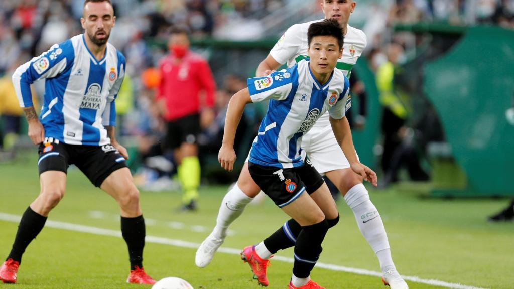 Wu Lei intenta ganar un balón en la banda ante Raúl Guti