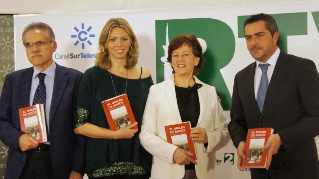 La escritora sevillana Carmen de la Rosa, vestida con chaqueta blanca, posa con una de sus novelas en Canal Sur.