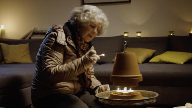 Una mujer intenta calentarse con velas tras un apagón.