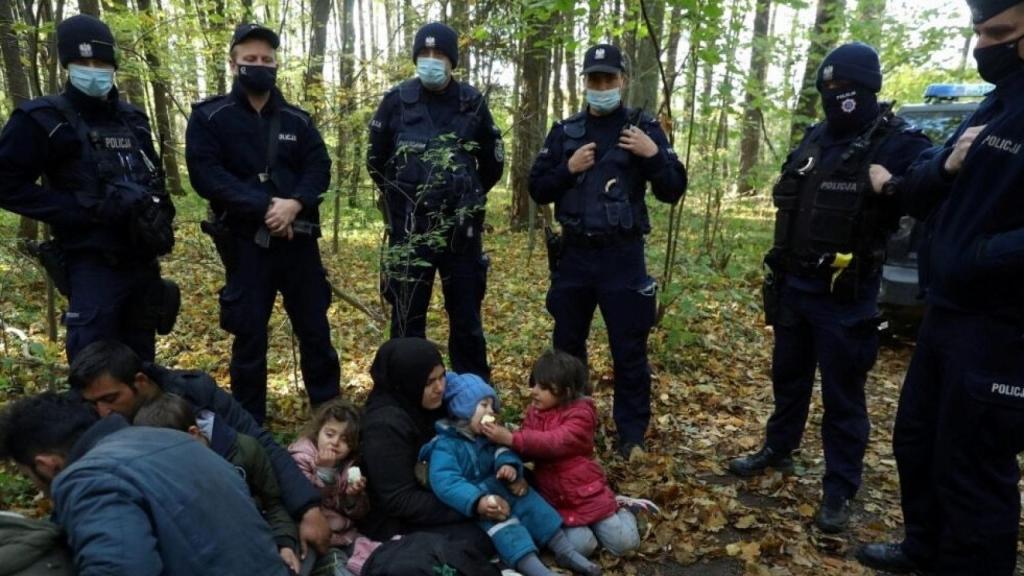 Una mujer iraquí rodeada de policías de frontera polacos tras cruzar desde Bielorrusia.