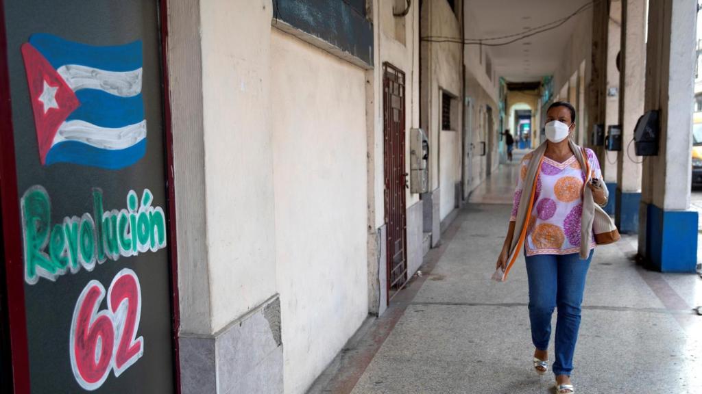 Una mujer camina hoy junto a un dibujo en apoyo a la Revolución Cubana, en La Habana.