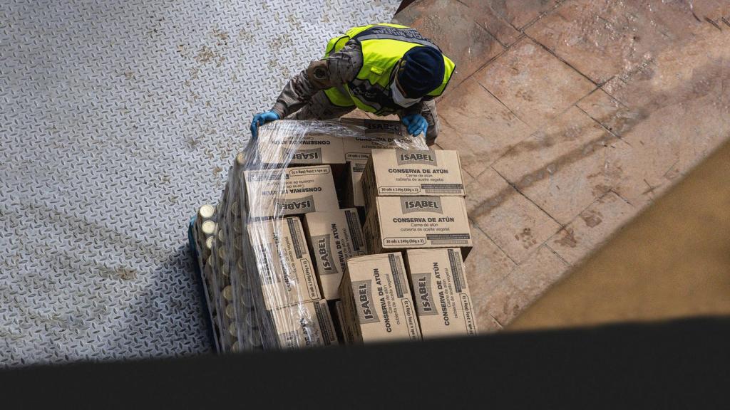 Un operario con cajas de atún envasado.