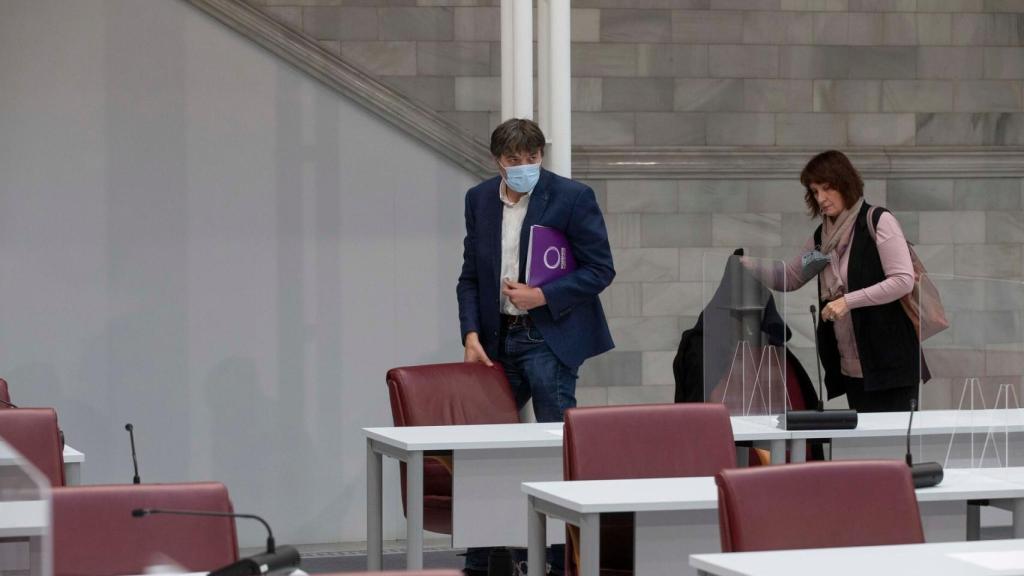 Los dos diputados de Podemos saliendo de la Asamblea para no escuchar la intervención del PP en el pleno..