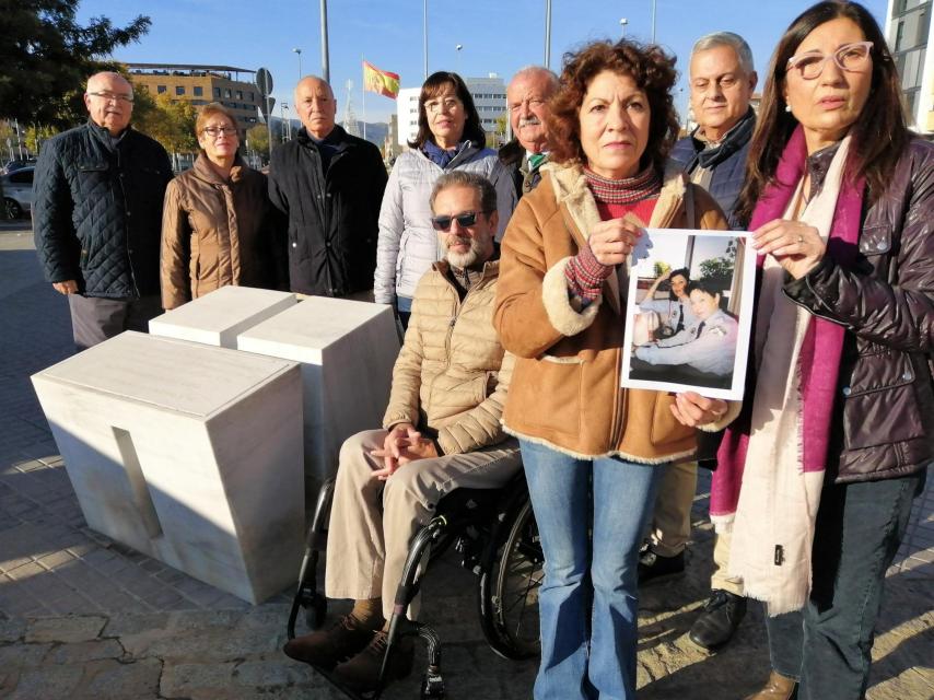 En primer plano, Elisa García y María Jesús Muñoz muestran una foto de sus hermanas Mari Ángeles y Marisol, junto al monolito en Córdoba que las recuerda en el lugar donde las mató  el jefe de los atracadores. Detrás, de izquierda a derecha, Juan Mata, Joaquina García, Ismael García, Charo López, Manuel Castaño, Ignacio Mata y Bernardo Ruiz.