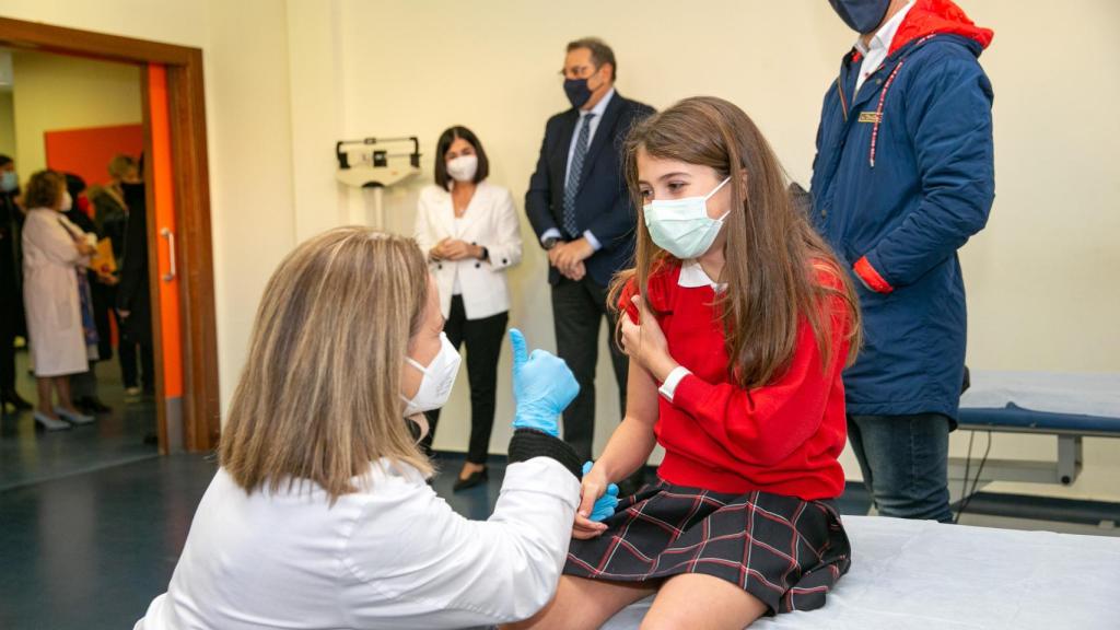 Una de las niñas que han sido vacunadas este miércoles en Toledo, siendo observada desde el fondo por la ministra.