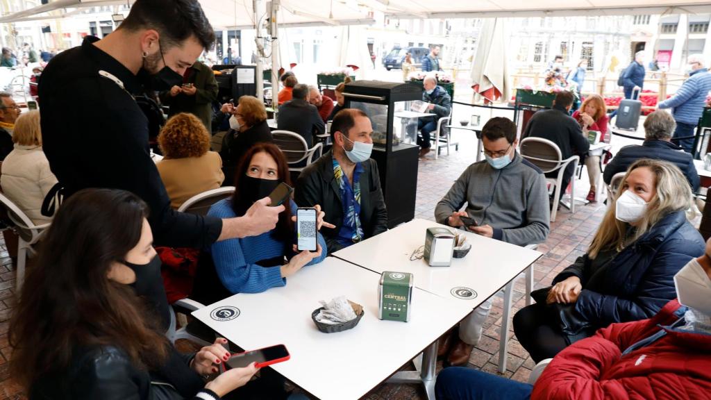 Un camarero pide certificado a los clientes en una mesa en la terraza de un bar.