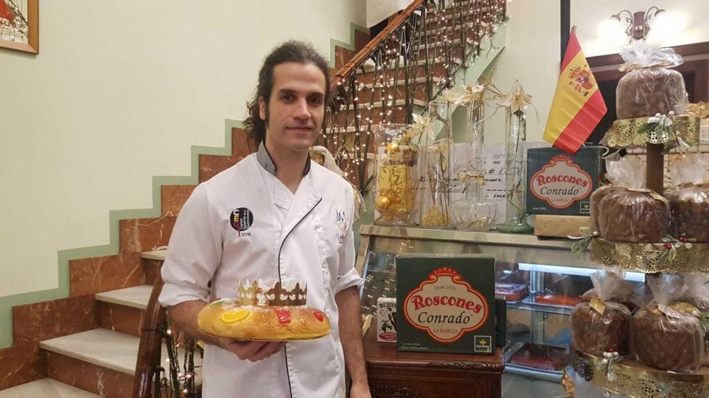 El confitero, Sergio González, con uno de los roscones que esconde en su interior el premio millonario