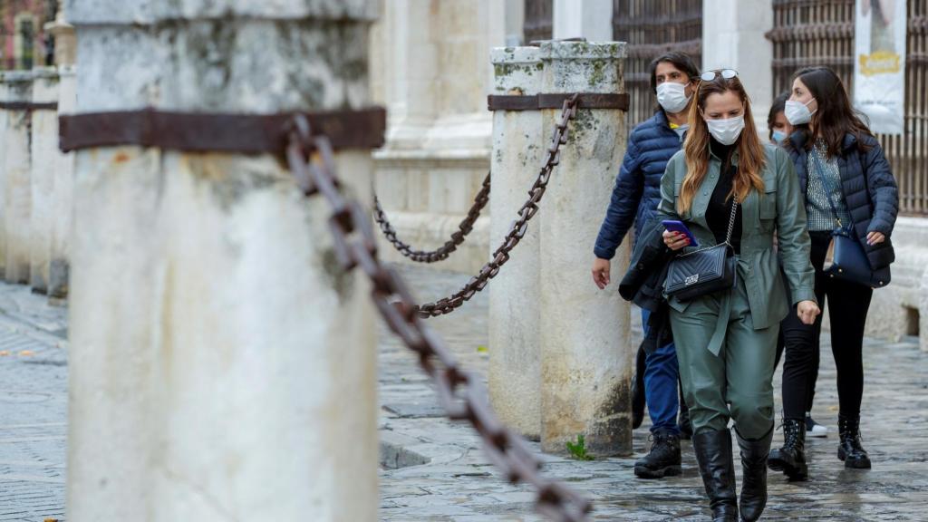 Varias personas con mascarillas junto a las columnas de la Catedral de Sevilla