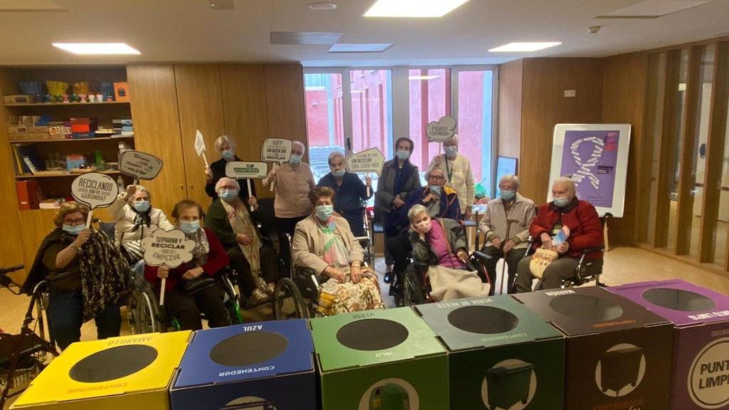 Personas mayores en una residencia con papeleras de separación de residuos