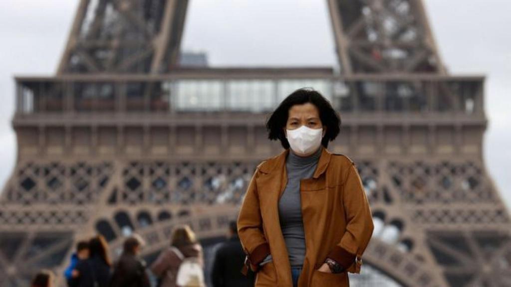 Una mujer con mascarilla, cerca de la Torre Eiffel.