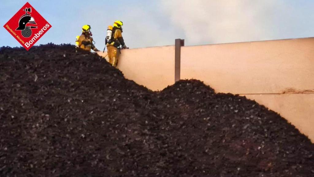 Dos bomberos subidos a una montaña de neumáticos.