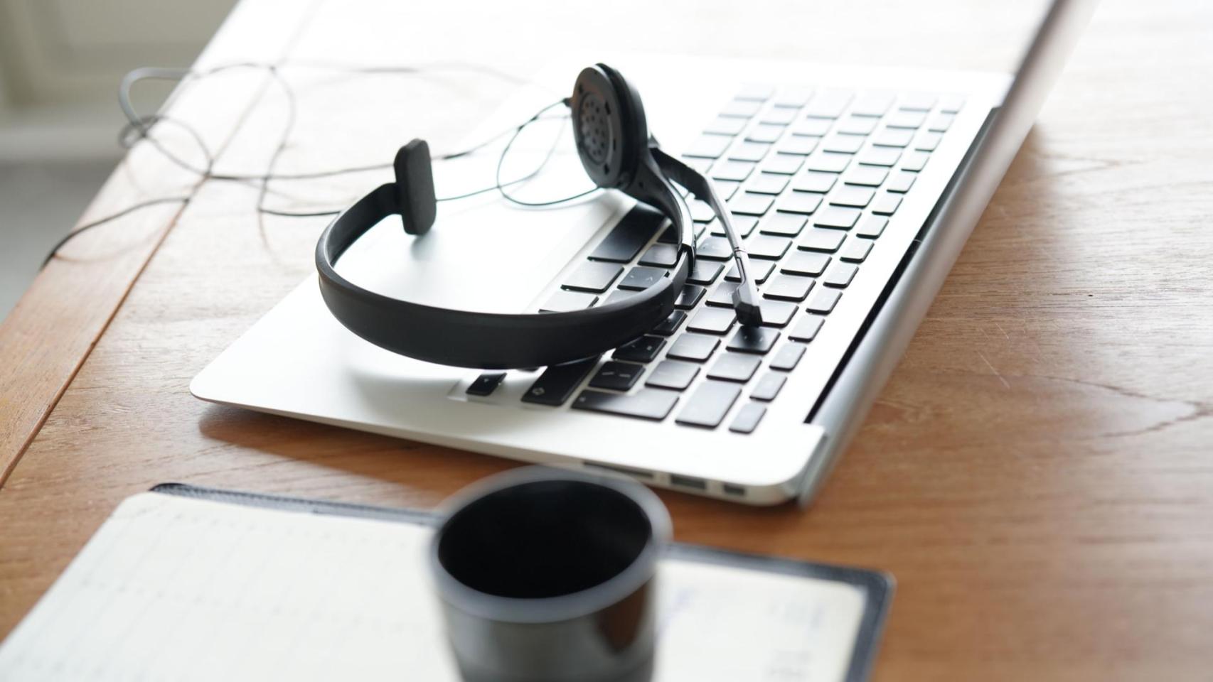 Unos cascos de un trabajador de servicios de atención al cliente sobre un teclado de ordenador.