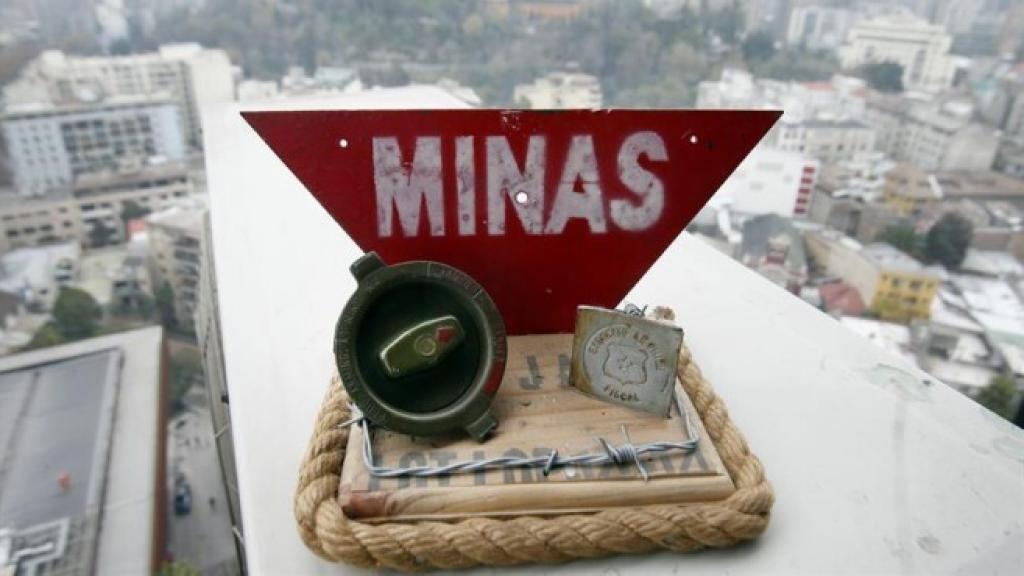 Vista de una maqueta con partes de una mina antipersona y una señal de advertencia.