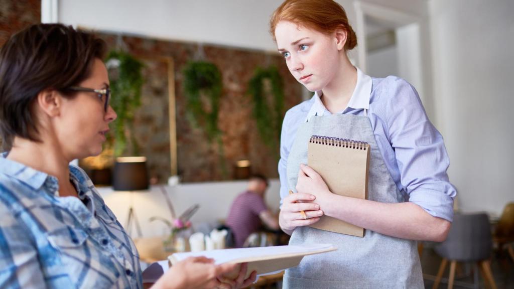 Una mujer pide una hoja de reclamaciones en un restaurante.