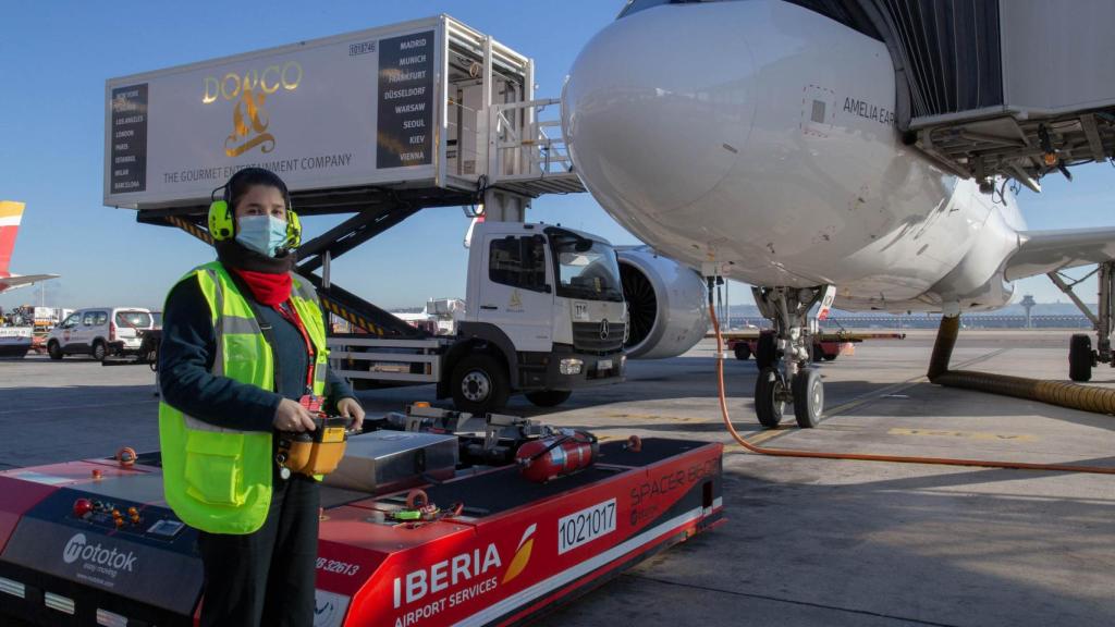 Sara Gutiérrez Chamón posa junto al mototok. Por detrás, trabajadores cargan el catering para el vuelo.