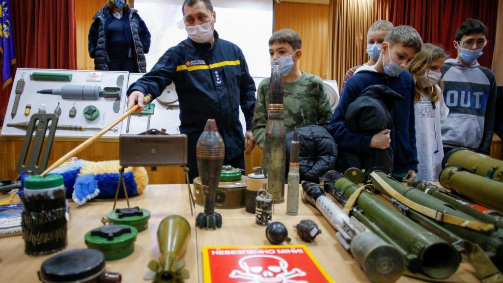 Un zapador del Servicio Estatal de Emergencias de Ucrania muestra simulacros de artefactos a los estudiantes durante la formación sobre amenazas de bomba en una escuela local de Kiev.
