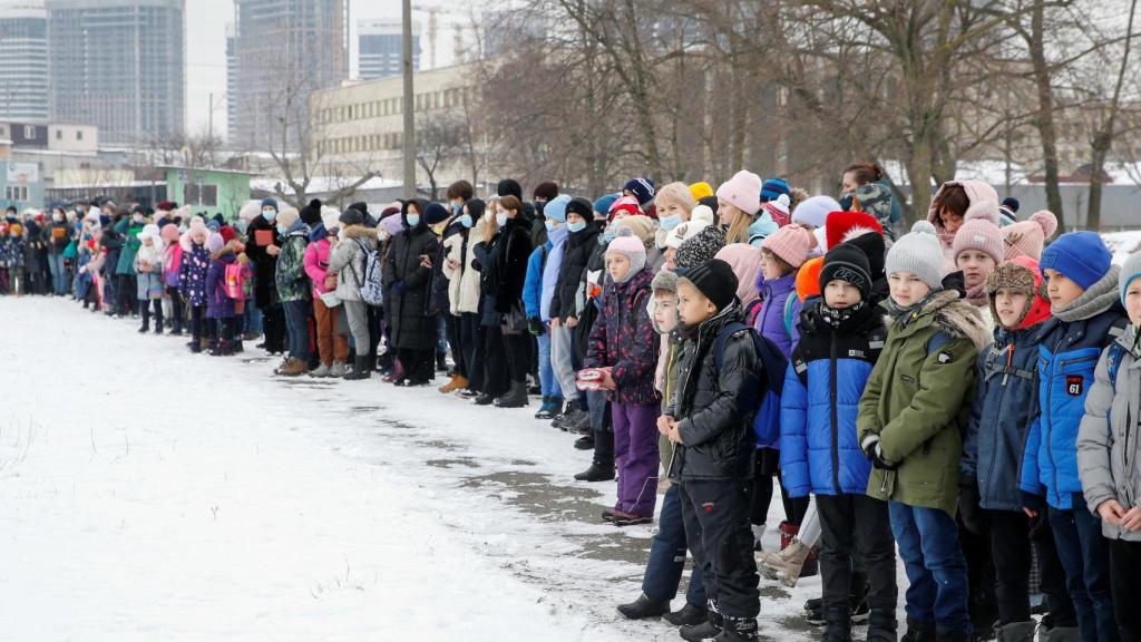 Profesores y alumnos después de una evacuación del edificio de una escuela local durante un entrenamiento de amenaza de bomba y emergencia en Kiev.