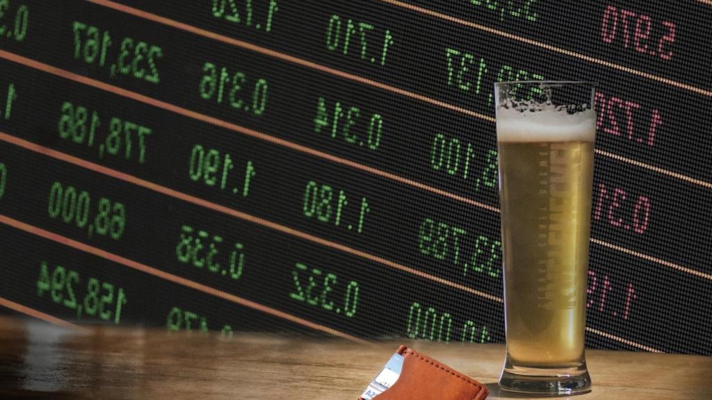 La barra de un bar con una pantalla de cotizaciones de fondo.