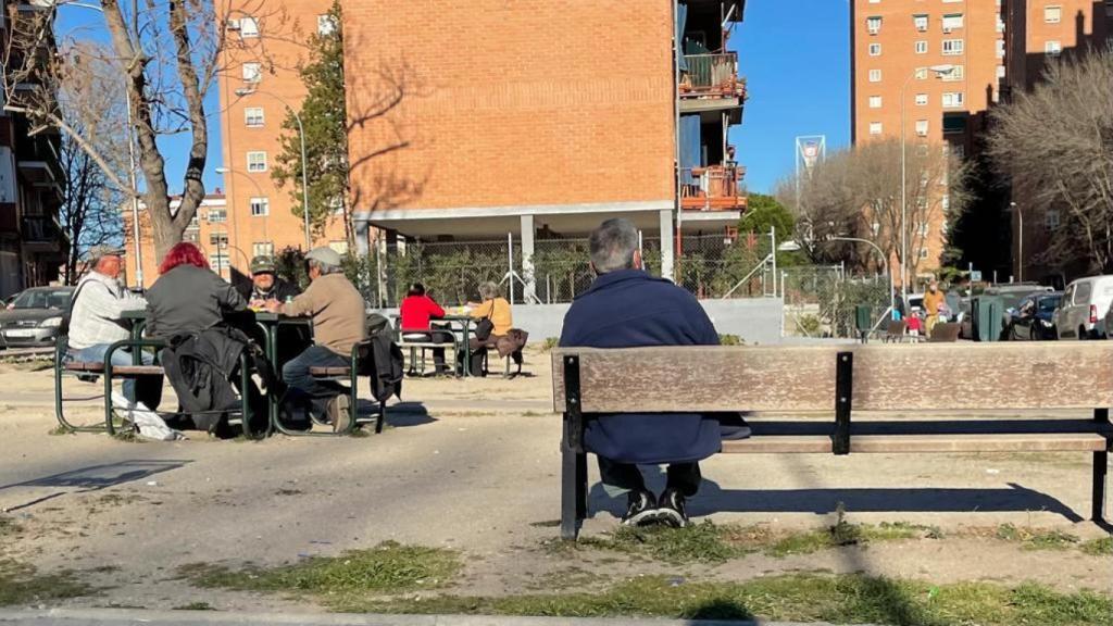 Unos vecinos juegan al dominó, mientras otros toman el sol en el parque.