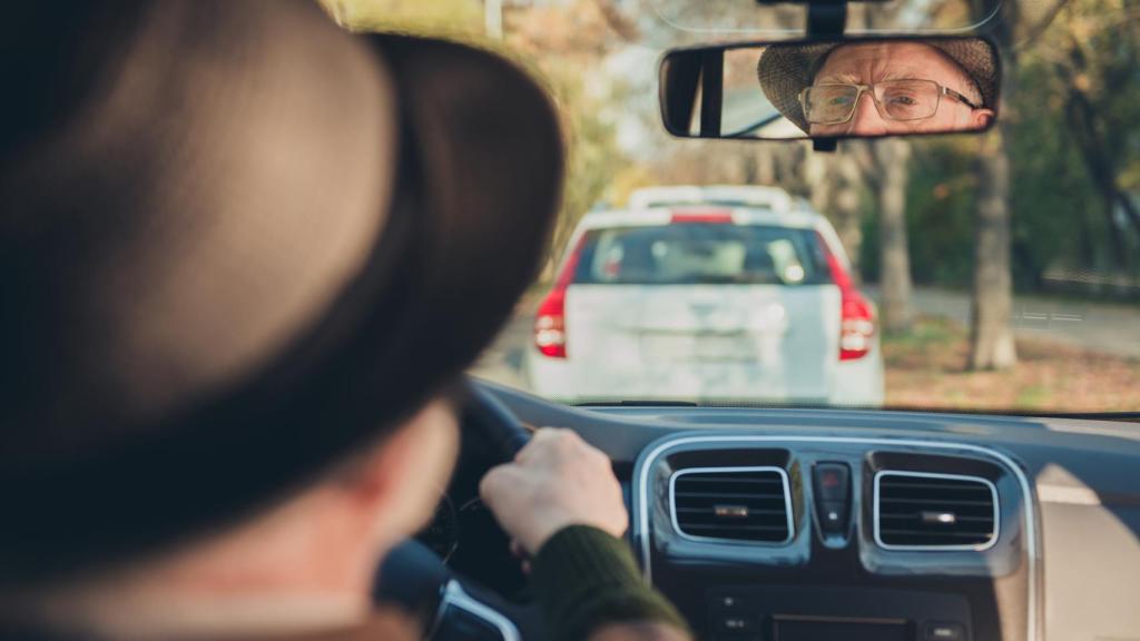 Una persona mayor conduce su vehículo.