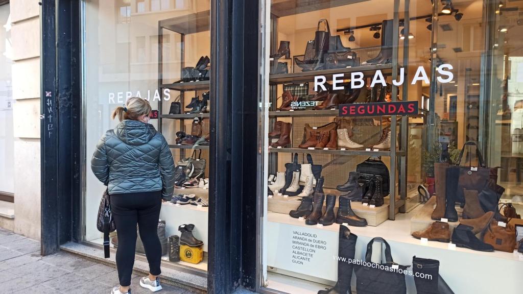 Una mujer observa los productos rebajados de un comercio desde la calle