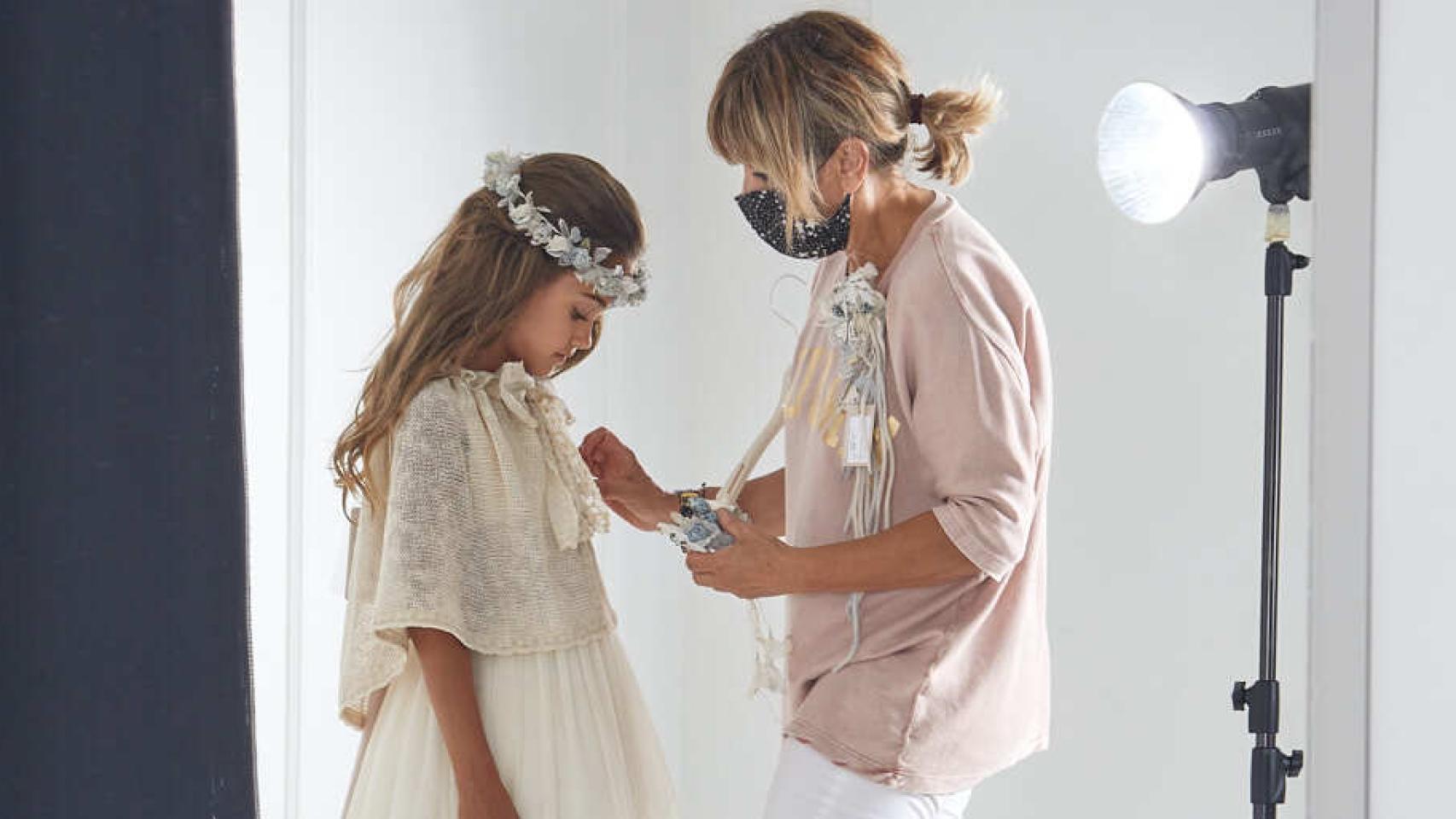 Hortensia Maeso coloca el traje bien a una niña antes de una sesión de fotos.