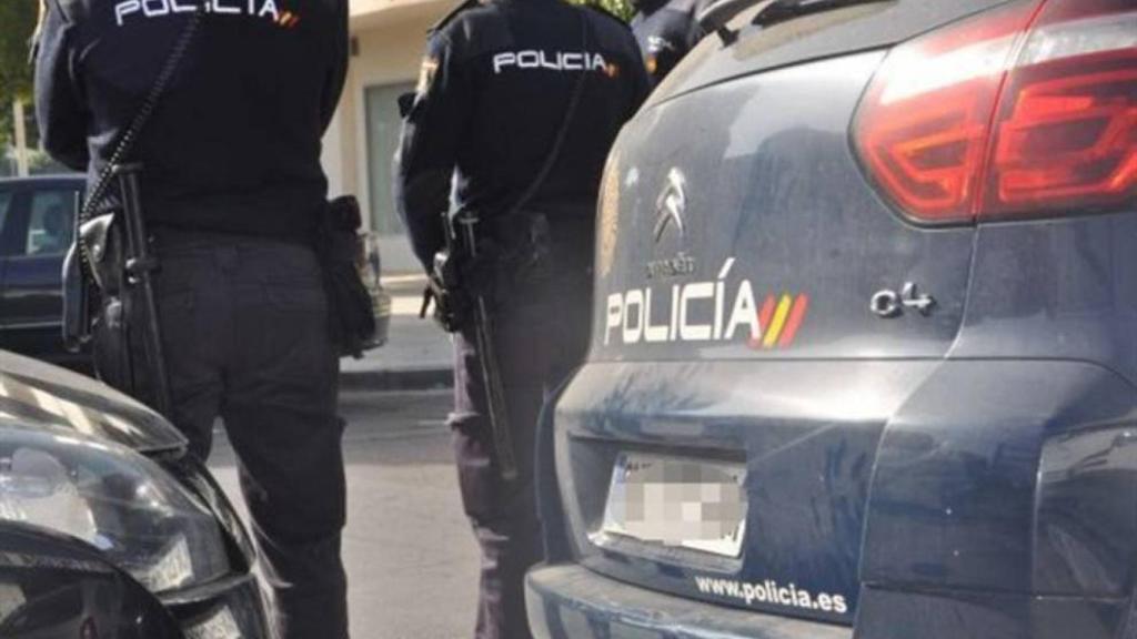 Dos policías nacionales junto a los vehículos