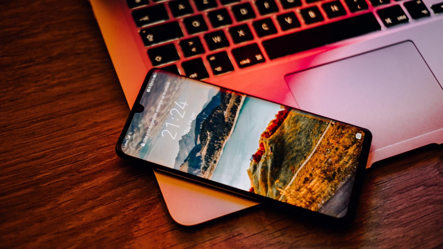 Un smartphone apoyado sobre un ordenador portátil