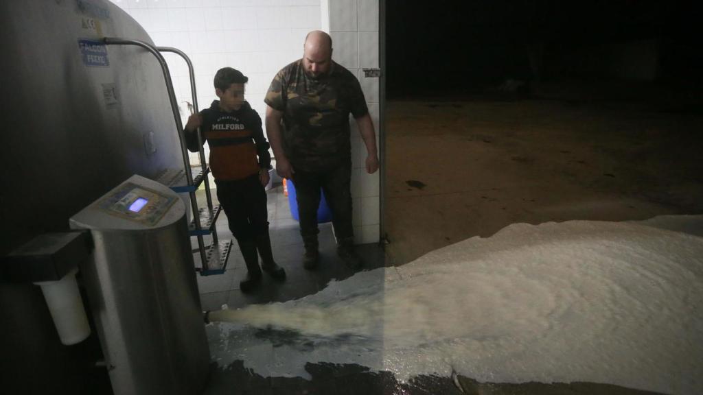 Un ganadero vierte leche al suelo.
