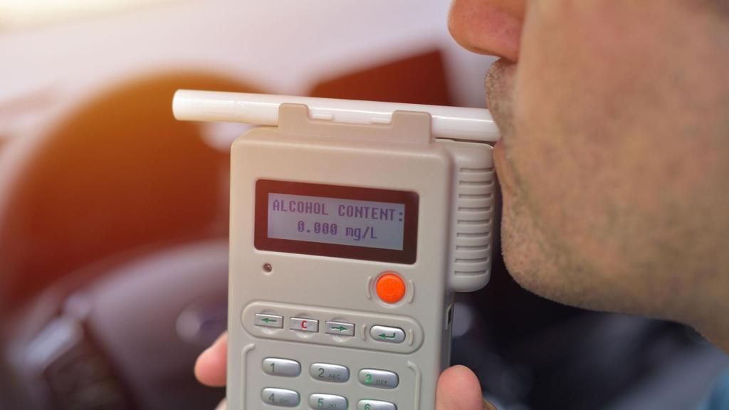Una persona soplando en el alcoholímetro antiarranque.