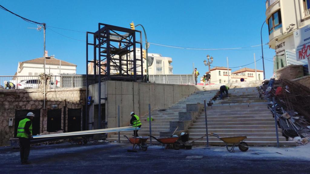 Dos obreros trasladan una de las planchas que serán usadas para vallar la Tribuna de los Pobres.