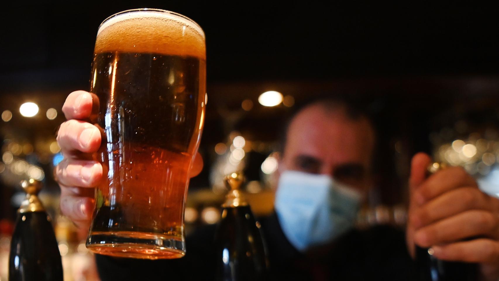 Un camarero sirve una jarra de cerveza.