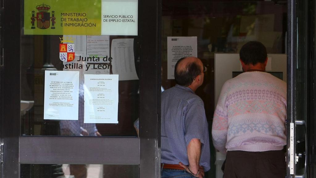 Varias personas miran carteles en con anuncios de empleo