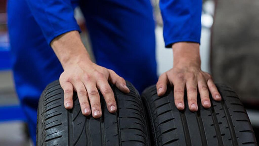 Un hombre sujetando dos neumáticos.