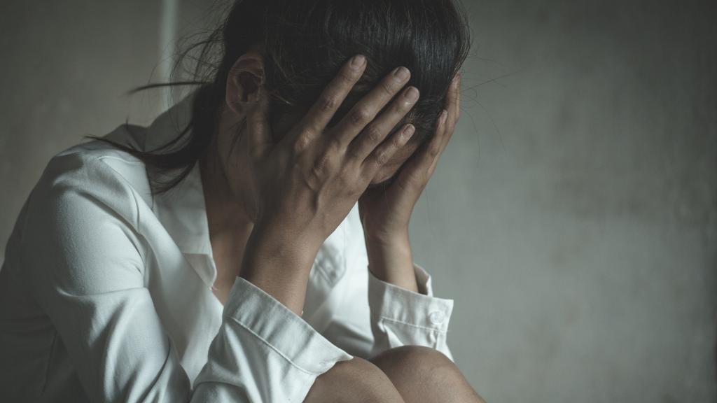 Una joven se tapa la cara mientras llora asustada.