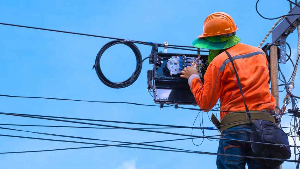 Operario instalando fibra óptica en imagen de archivo.