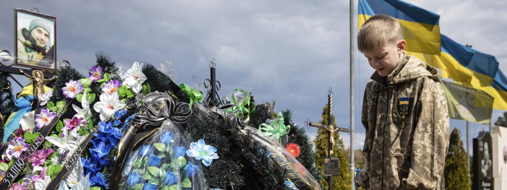 Un niño llora en la tumba de su padre.