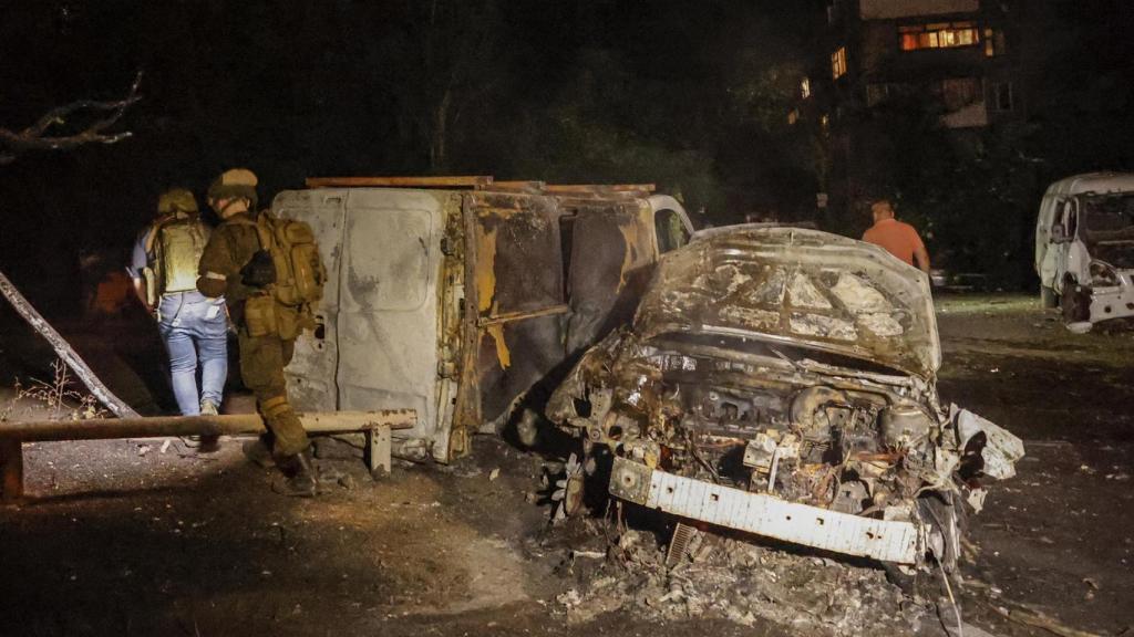 Locales ucranianos examinan coches destrozados.